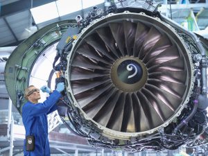 Engineers working on aircraft engine in aircraft maintenance factory lavoro